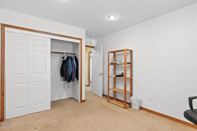 bedroom featuring baseboards, a closet, and light colored carpet