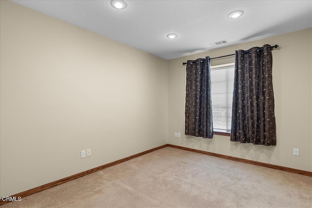 unfurnished room with light carpet, baseboards, visible vents, and a textured ceiling