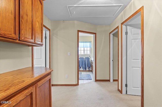 corridor featuring baseboards and light colored carpet