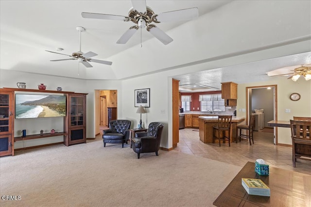 living area featuring light carpet, ceiling fan, a tray ceiling, and light tile patterned floors