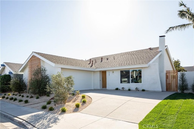 ranch-style home featuring roof with shingles, a chimney, stucco siding, concrete driveway, and a garage