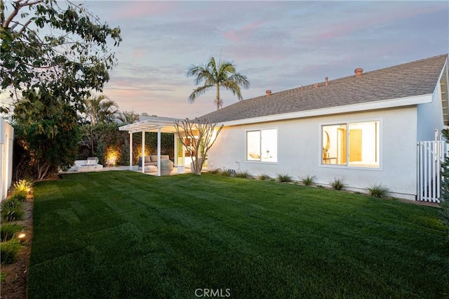 rear view of property featuring a lawn, stucco siding, and a pergola