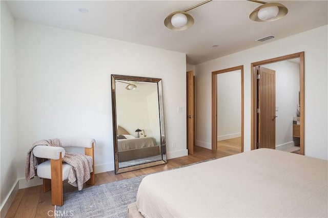 bedroom featuring baseboards, visible vents, and wood finished floors