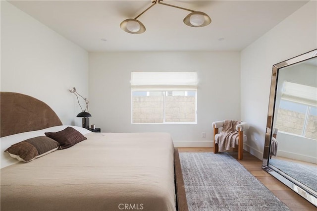 bedroom featuring multiple windows, wood finished floors, and baseboards