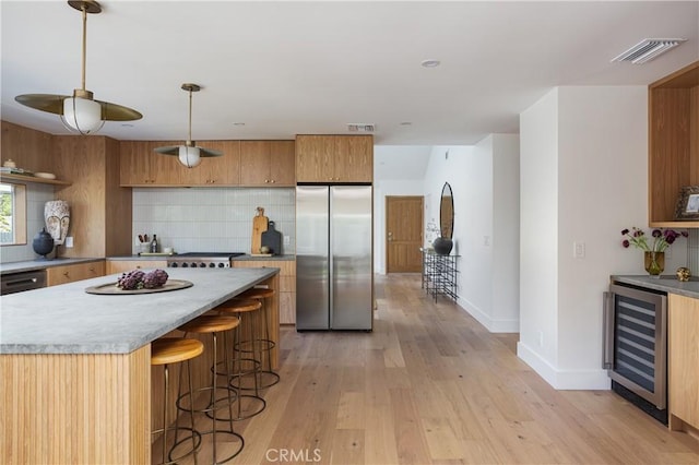 kitchen featuring beverage cooler, visible vents, decorative backsplash, and stainless steel refrigerator