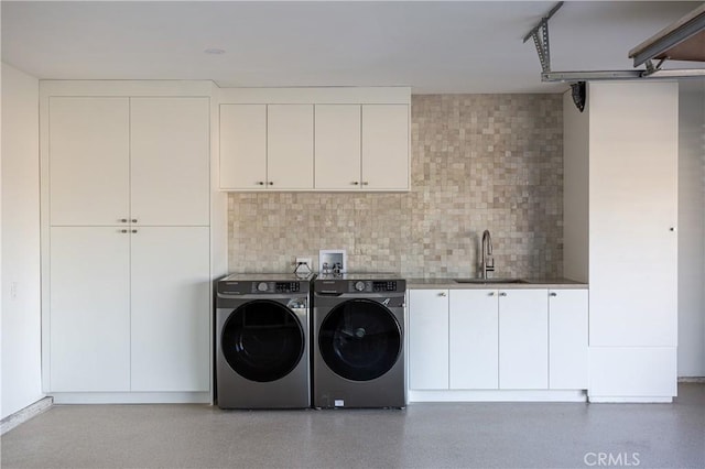 washroom featuring cabinet space, a sink, and washing machine and clothes dryer