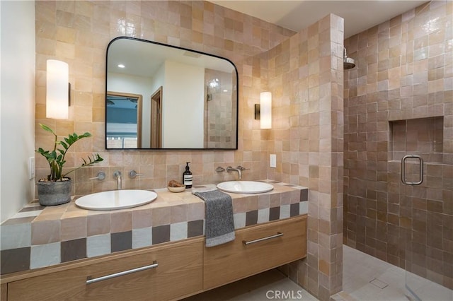 full bathroom with a stall shower, tile walls, and a sink