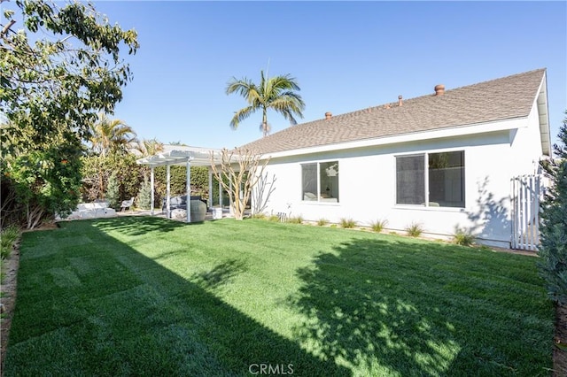 back of house with a yard, roof with shingles, stucco siding, and a pergola