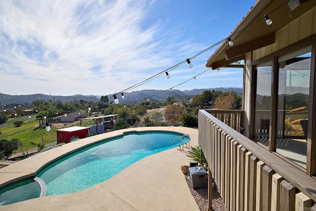 view of pool with a pool with connected hot tub, a patio area, and a mountain view