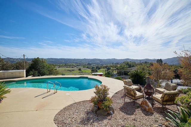 pool featuring fence, a mountain view, and a patio