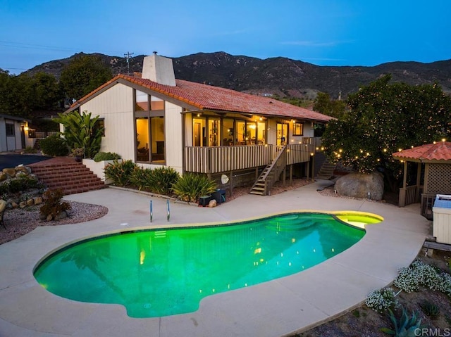 pool with a deck with mountain view, a patio area, and stairway