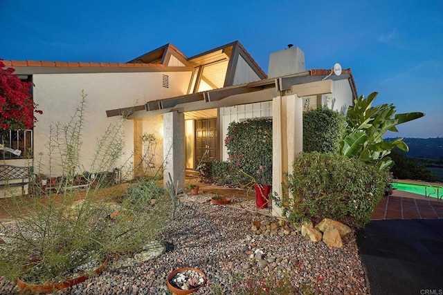 entrance to property with a chimney and stucco siding