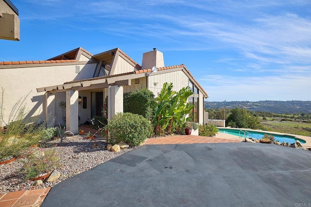 view of property exterior featuring a chimney, a patio area, and an outdoor pool