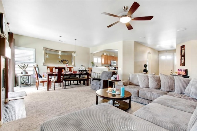 living area with light carpet, plenty of natural light, and arched walkways