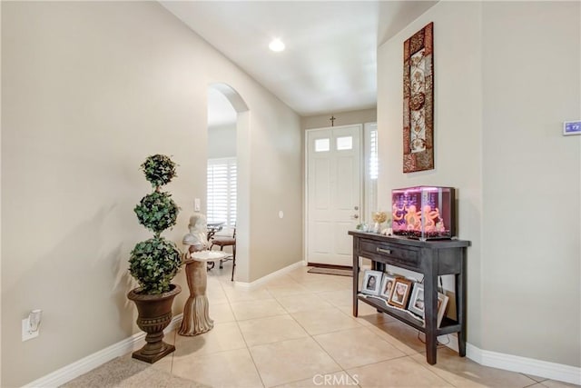 entrance foyer with light tile patterned floors, baseboards, and arched walkways