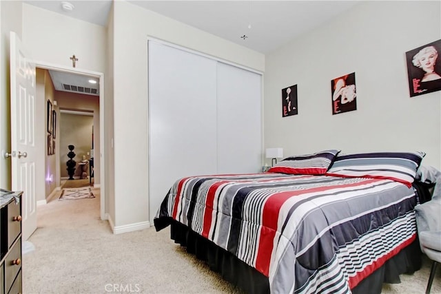 bedroom with light carpet, a closet, visible vents, and baseboards