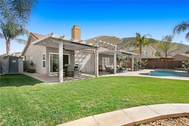 rear view of property with a pergola, fence, a lawn, stucco siding, and a chimney