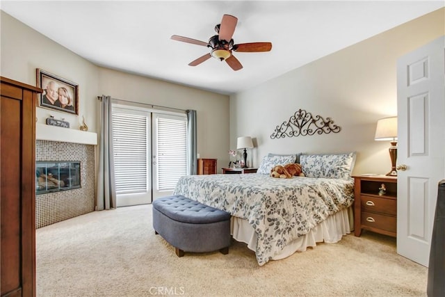 bedroom with light carpet, a fireplace, and a ceiling fan