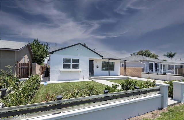 view of front facade featuring a fenced front yard, a front lawn, and stucco siding