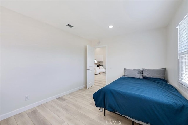 bedroom featuring baseboards, multiple windows, visible vents, and light wood-style floors