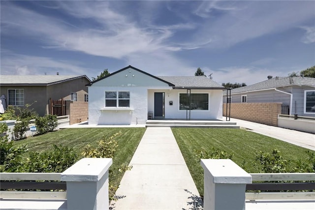 view of front of house with covered porch, a fenced front yard, a front yard, and stucco siding