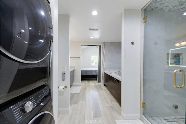 bathroom featuring stacked washer / drying machine, visible vents, a shower stall, ensuite bath, and wood finished floors