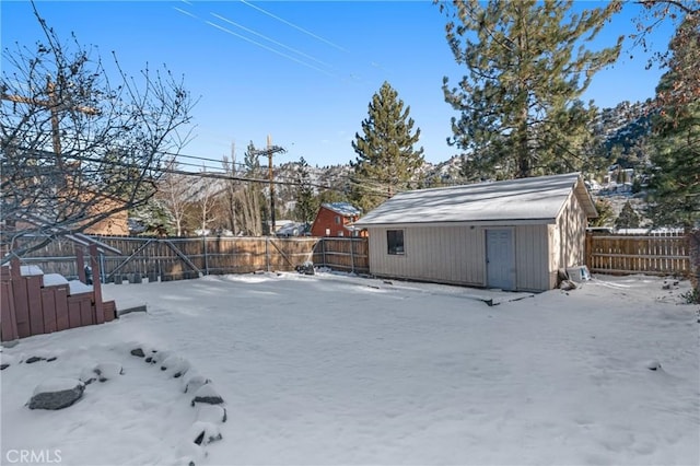 snowy yard with a fenced backyard and an outdoor structure