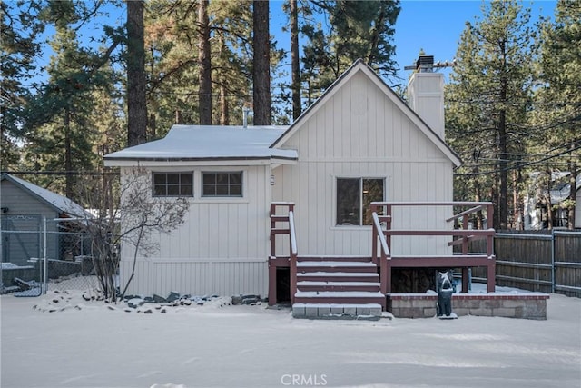 view of front of house featuring a chimney, fence, and a wooden deck