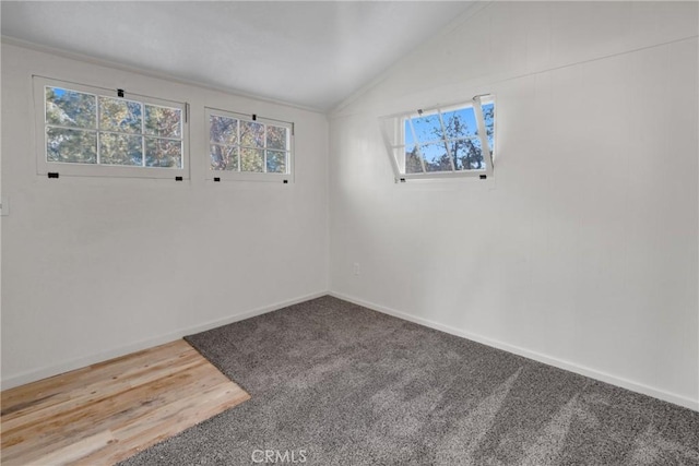 spare room with vaulted ceiling, baseboards, and wood finished floors