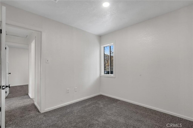 unfurnished room with baseboards and dark colored carpet