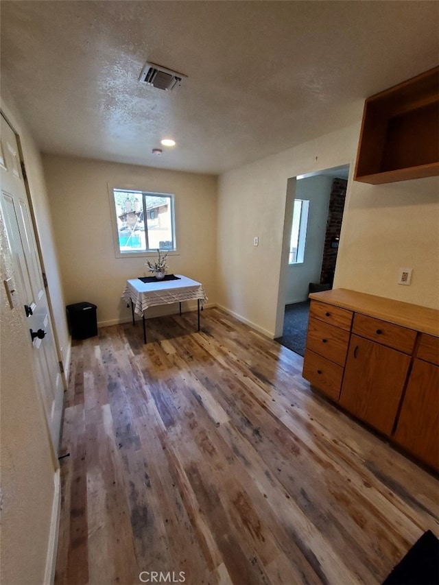 unfurnished bedroom with light wood-style floors, baseboards, visible vents, and a textured ceiling