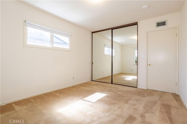 unfurnished bedroom with carpet floors, a closet, and visible vents