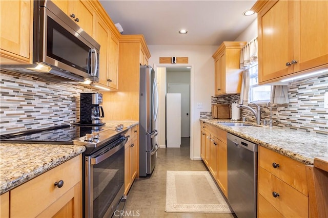 kitchen featuring light stone counters, stainless steel appliances, recessed lighting, decorative backsplash, and a sink