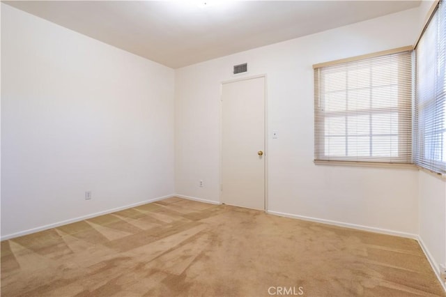 unfurnished room featuring visible vents, light carpet, and baseboards