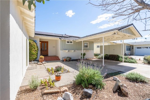 exterior space featuring roof mounted solar panels, concrete driveway, and stucco siding