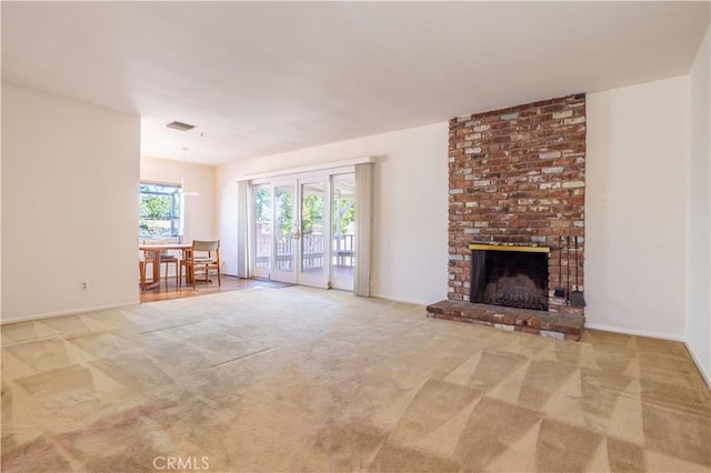 unfurnished living room featuring a brick fireplace, carpet flooring, and baseboards