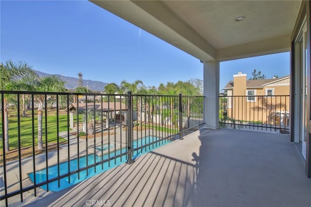 balcony featuring a pool with connected hot tub, a mountain view, and a patio