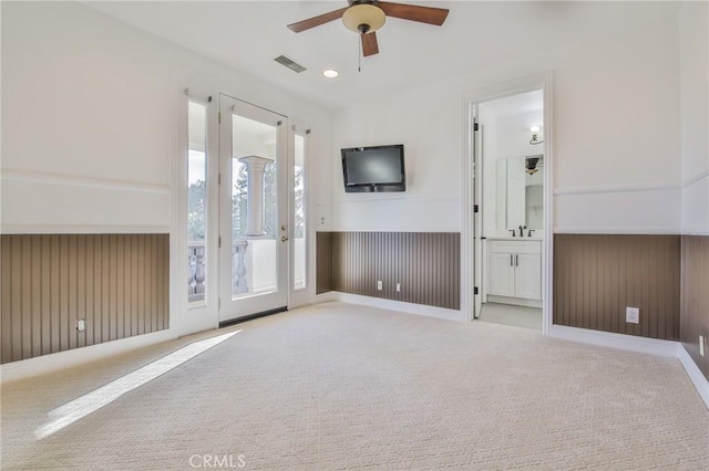 unfurnished living room featuring visible vents, a ceiling fan, carpet flooring, wood walls, and recessed lighting