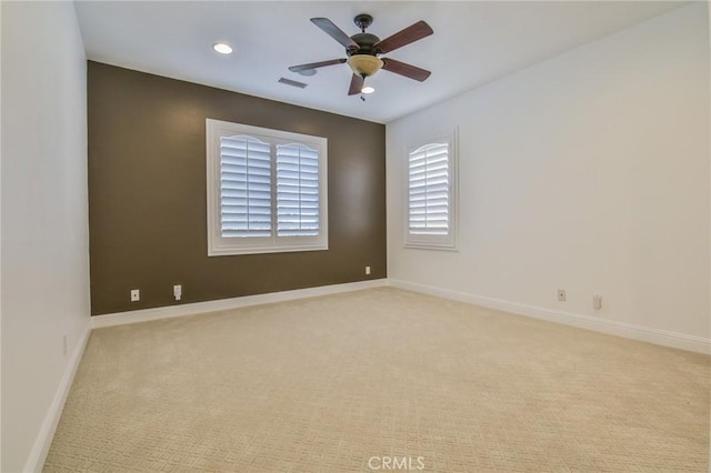 empty room with ceiling fan, light carpet, visible vents, and baseboards