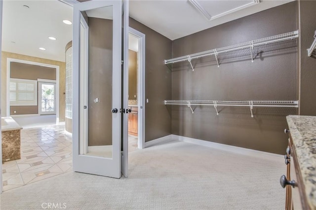 walk in closet with light carpet and light tile patterned floors