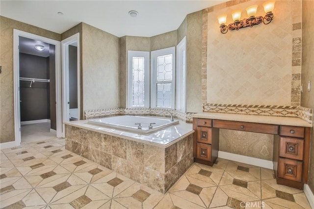 bathroom featuring tile patterned flooring, baseboards, a walk in closet, and a bath