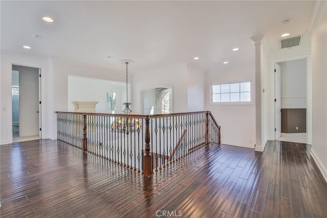 hallway featuring a chandelier, wood finished floors, visible vents, and crown molding