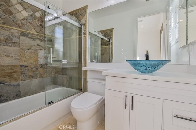 full bath with toilet, shower / bath combination with glass door, and vanity