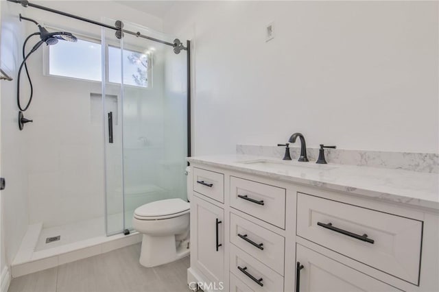 bathroom with a stall shower, vanity, and toilet