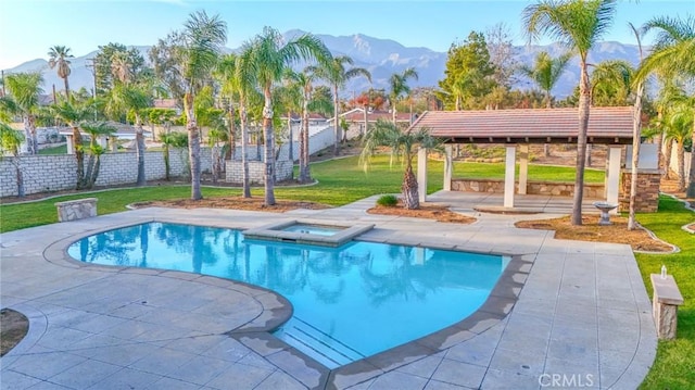 view of swimming pool featuring a mountain view, fence, a pool with connected hot tub, a lawn, and a patio area