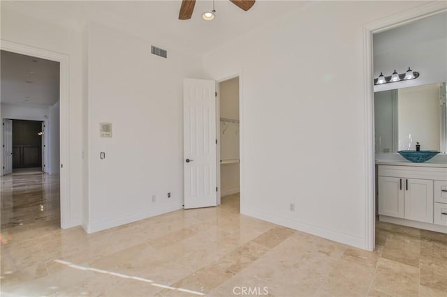 unfurnished bedroom featuring baseboards, visible vents, ensuite bath, a spacious closet, and a sink