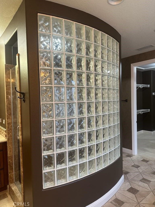 interior space with a stall shower, visible vents, a textured ceiling, and tile patterned floors