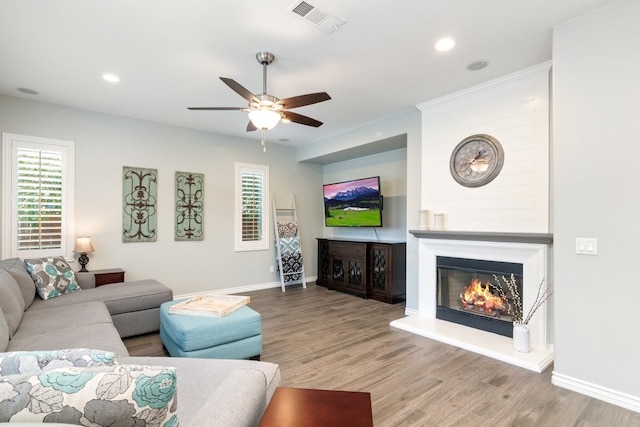 living area featuring wood finished floors, plenty of natural light, a glass covered fireplace, and visible vents