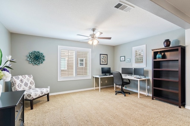 home office featuring baseboards, visible vents, light colored carpet, ceiling fan, and a textured ceiling