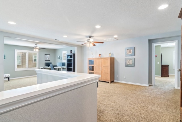 hallway with light carpet, baseboards, a textured ceiling, and recessed lighting